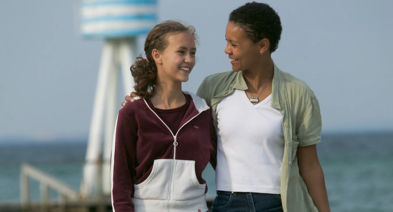 Ein junges Mädchen und eine farbige Frau gehen Arm in Arm spazieren